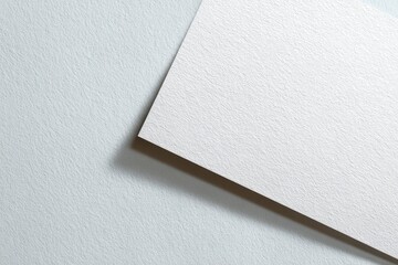 Blank white paper sheet angled on light-gray textured background