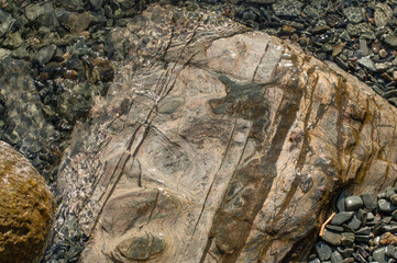 A large flat stone lying on the bottom of a lake under a layer of clear transparent water