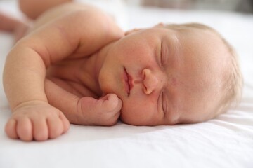 Cute newborn baby sleeping on bed indoors