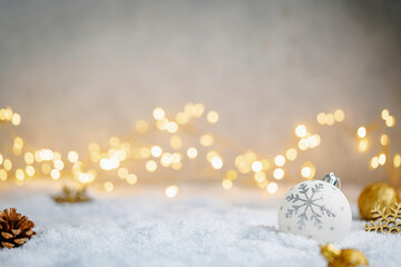Fototapeta premium Christmas Holiday background with snow, fir tree and decorations with christmas light behind. Christmas white and golden balls on a winter festive background.