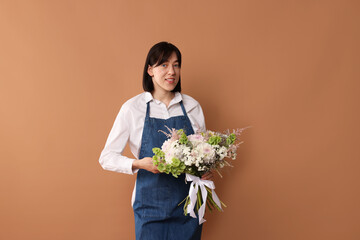 Florist with beautiful bouquet of flowers on dark beige background
