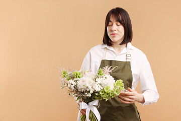 Florist with beautiful bouquet of flowers on beige background, space for text