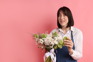 Florist with beautiful bouquet of flowers on pink background, space for text