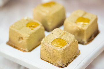 Square golden mousse cakes with a glossy fruit jelly center, showcasing luxury patisserie design and festive presentation.