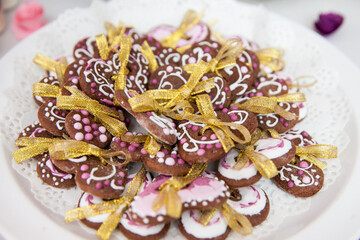 A plate of heart-shaped gingerbread cookies decorated with white and pink icing, tied with golden ribbon bows, served on a lace doily for a festive celebration.