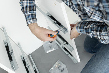 Close up of a Man Assembling a drawer slider Furniture using a screwdriver