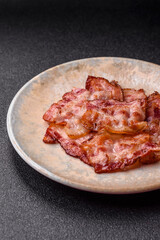 Cooked crispy fried pork bacon strips for a hearty breakfast. Fried bacon strips