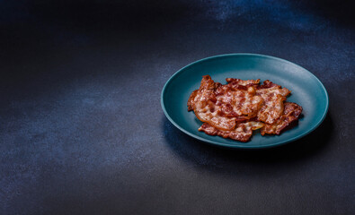 Cooked crispy fried pork bacon strips for a hearty breakfast. Fried bacon strips