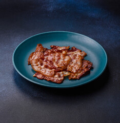Cooked crispy fried pork bacon strips for a hearty breakfast. Fried bacon strips