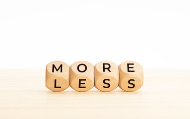 More and less word on changing wooden blocks. Copy space. White background