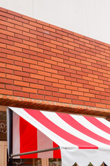 Striped red awning with red brick wall of cafe,Red White Tents, market umbrella,Front tent roof for shop showcase Cafe or restaurant.