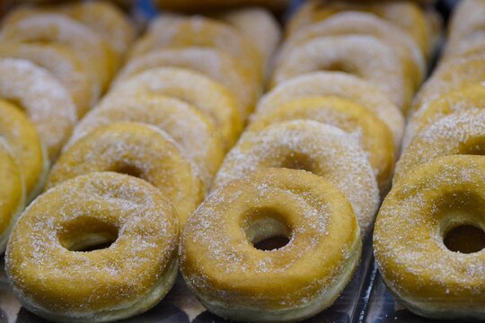 Close-up of fresh donuts sprinkled with powdered sugar, laid out in neat rows on top of each other. Sweet pastries on an appetizing background. Food photos baking ads or projects dedicated to desserts