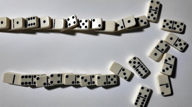 Falling dominoes in slow motion. Close-up of the domino effect. Chain reaction concept.