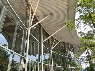 view of a curved, modern glass and steel building supported by multiple pillars.