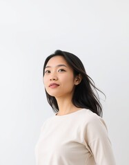 Fototapeta premium Portrait of asian woman with dark hair looking up against a white background in studio