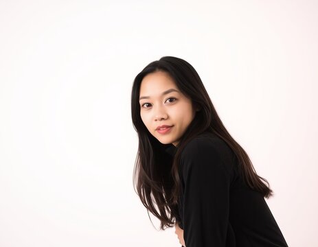 Portrait of a young woman with long black hair wearing a black top against white background