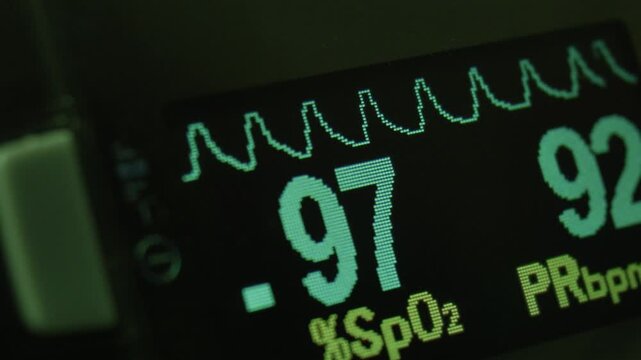 Pulse oximeter showing oxygen saturation and heart rate on screen. Medical device measuring oxygen saturation and heart rate, displaying vital signs on a digital screen