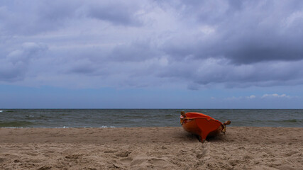 A red boat on the seashore. A lonely boat on the shore.