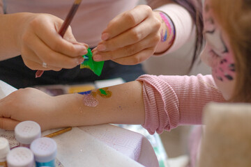 selective focus. decorative cosmetics for children and adults. holy Flash tattoo. Transfer tattoos for kids. master makes a girl a transfer temyporar glitter tattoo with sequins. childreay. Animators