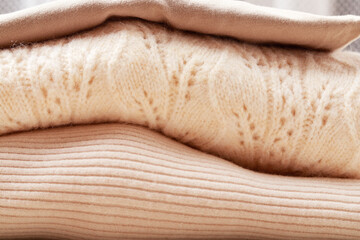 Soft sweaters and blouses folded into a pile.