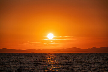 Sunset over the sea
Golden sun setting behind the mountains with reflection on the sea surface.
