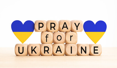 Pray for Ukraine message on wooden blocks and flag of Ukraine on heart shape