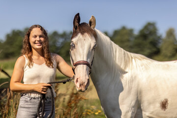 Obraz premium Smiling young woman bonding with a Paint Horse outdoors in summer nature