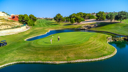 Golfers putting on green surrounded by water in golf course © unai