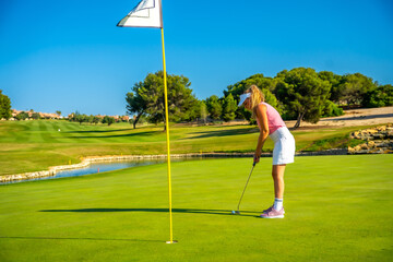 Golfer putting ball on green in sunny day on golf course