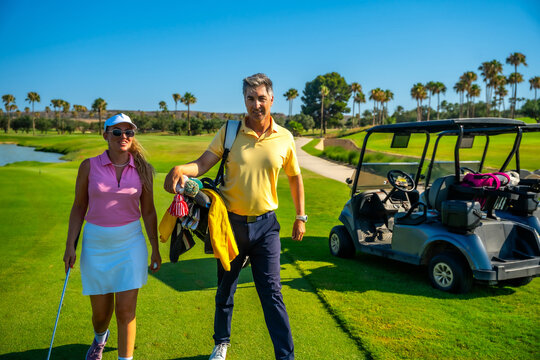 Golfers walking on golf course with golf cart in background