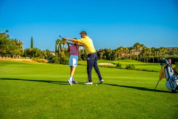 Golf instructor helping golfer woman with swing on golf course