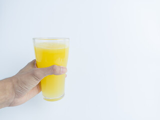 Hand holding a tall glass of fresh orange juice on white background with copy space. Refreshing citrus drink concept for healthy lifestyle, food, and beverage design.

