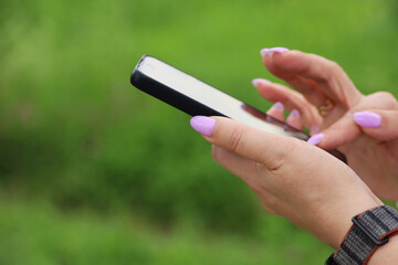 Smartphone in female hands, woman using mobile phone outdoor at summer