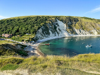 Lulworth Cove bay, beach and cliffs view . The Jurassic Coast is a World Heritage Site on the English Channel coast of southern England. Dorset, UK. crowded beach, public beach.