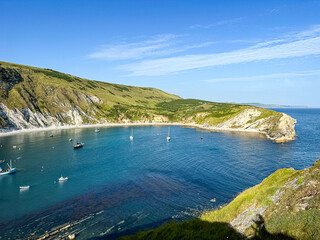 Lulworth Cove bay, beach and cliffs view . The Jurassic Coast is a World Heritage Site on the English Channel coast of southern England. Dorset, UK. crowded beach, public beach.
