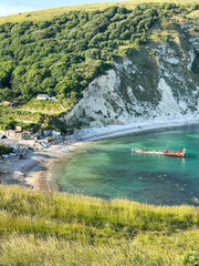 Lulworth Cove bay, beach and cliffs view . The Jurassic Coast is a World Heritage Site on the English Channel coast of southern England. Dorset, UK. crowded beach, public beach.