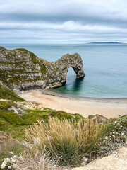 Early summer morning at Durdle Door in Dorset, England, UK. Durdle Door limestone arch on the Jurassic Coast in Dorset. Natural landmark. England. Pure clean clear water.