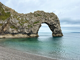 Early summer morning at Durdle Door in Dorset, England, UK. Durdle Door limestone arch on the Jurassic Coast in Dorset. Natural landmark. England. Pure clean clear water.