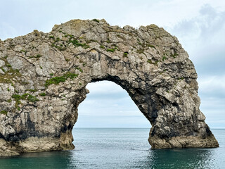 Early summer morning at Durdle Door in Dorset, England, UK. Durdle Door limestone arch on the Jurassic Coast in Dorset. Natural landmark. England. Pure clean clear water.