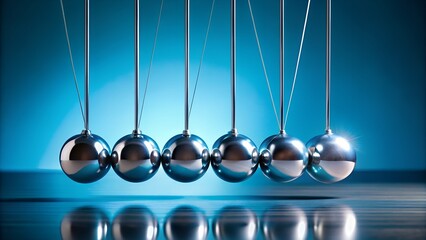 Newtons cradle, a classic physics toy demonstrating the conservation of momentum and energy through the collision of suspended metal balls, set against a dark blue background with reflections