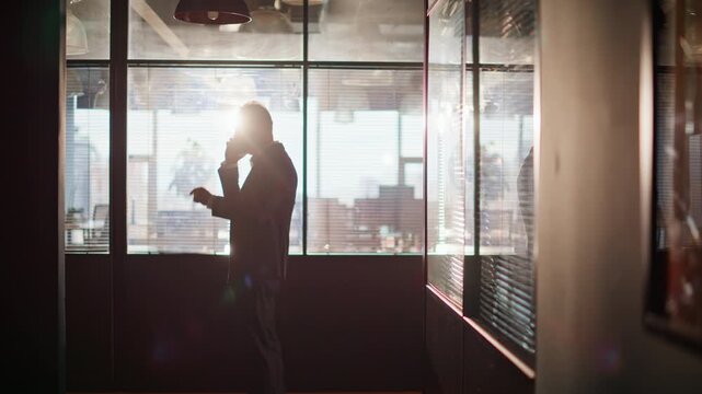 Silhouette manager talking cellphone in office corridor. Businessman finish call