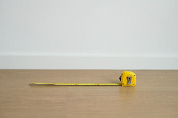 リフォーム,・引越し・間取りのイメージ　白い壁を背景にフローリングの床に置かれたメジャー