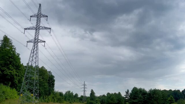 Steel transmission towers under dramatic overcast sky in rural Latvia near forest