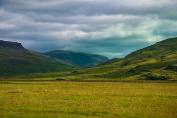 Fototapeta premium Icelandic green valley with dramatic storm clouds and mountains