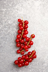 Fresh red currants arranged on a textured stone surface ready for culinary use and garnishing