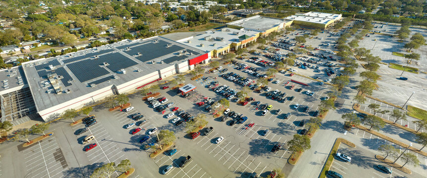 Large parking lot with many parked cars. Big carpark at supercenter shopping mall with lines and markings for vehicle places and directions