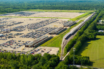 Automotive industry. Import or export of new cars by rail. Train auto racks at production factory warehouse. Vehicles for sale at logistics business parking lot