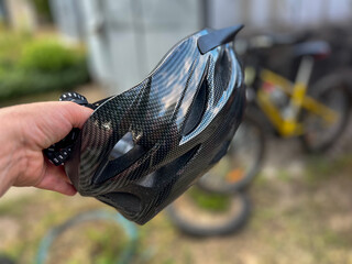 Cyclist holding carbon fiber bicycle helmet near bikes