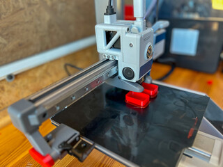 3d printer creating red plastic parts in workshop
