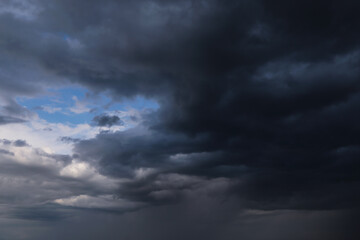 Epic Dramatic storm dark grey cumulus rain clouds with blue sky, background texture, thunderstorm